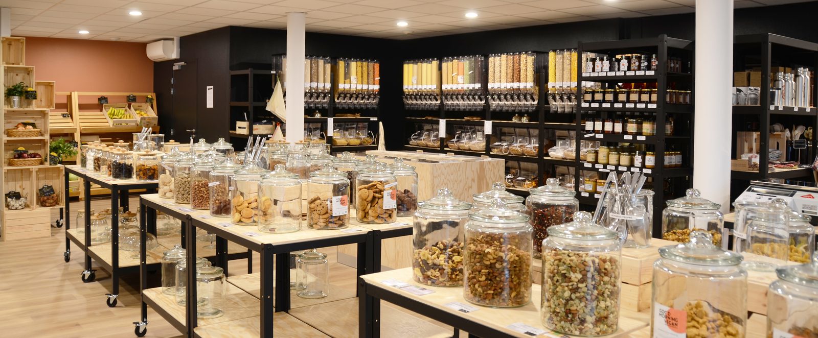 Vue générale de l'épicerie, ses tables de bocaux de vrac et ses étagères de produits