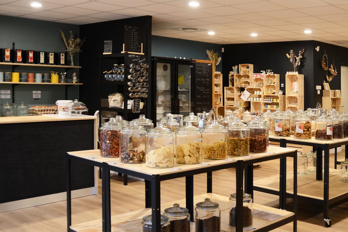 L'intérieur de l'épicerie : bocaux de vrac, étagères de bois et ardoises manuscrites